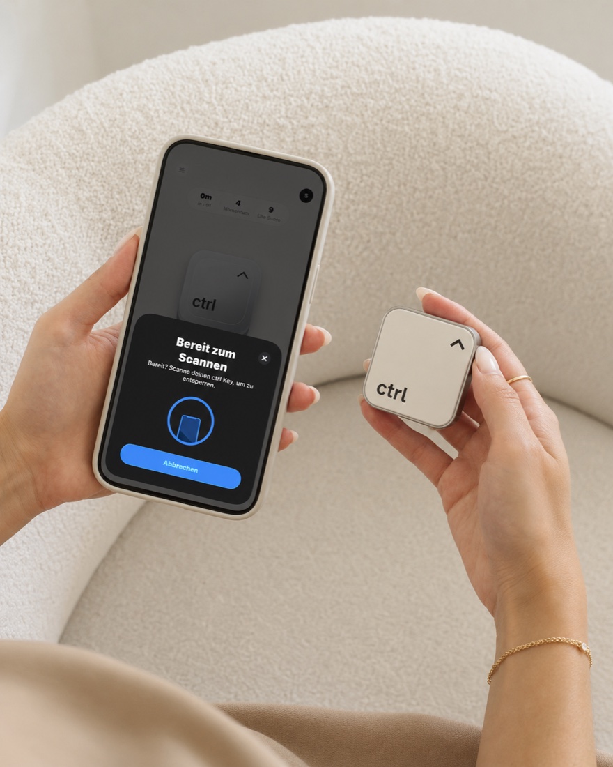 Eine Hand h&auml;lt das Handy mit der ctrl-App neben den ctrl key auf einem hellen Sessel